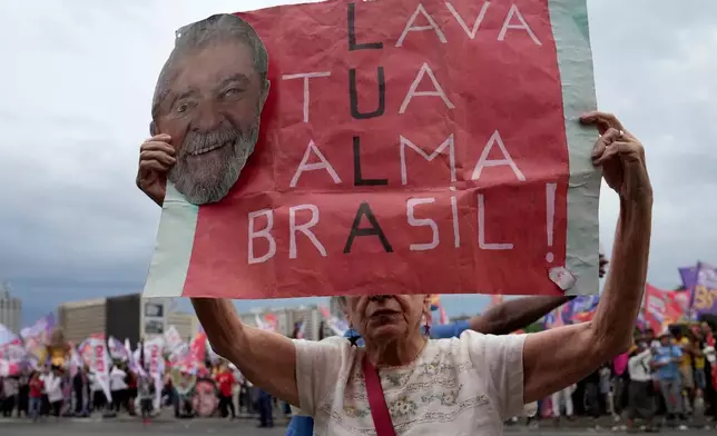 A supporter of Brazilian President Luiz Inacio Lula da Silva, who is running for reelection, holds a sign that reads "Lula, cleanse your soul, Brazil" during a campaign event at central bus station in Brasilia, Brazil, Friday, Oct. 2, 2026. (AP Photo/Eraldo Peres)