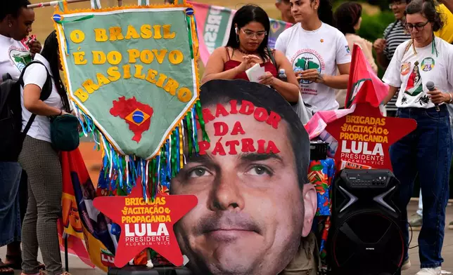 Supporters of Brazilian President Luiz Inacio Lula da Silva, who is running for reelection, display a large-headed effigy of presidential candidate Flavio Bolsonaro with a message in Portuguese that reads "Traitor of Brazil," during a campaign event at central bus station in Brasilia, Brazil, Friday, Oct. 2, 2026. (AP Photo/Eraldo Peres)