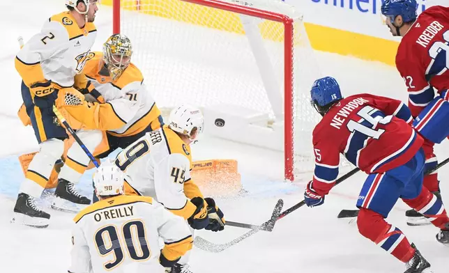 Montreal Canadiens' Alex Newhook (15) scores against Nashville Predators goaltender Juuse Saros, second from left, as Predators' Adam Wilsby (2), Ryan O'Reilly (90) and Reid Schaefer (49) defend and Canadiens' Chris Kreider (22) looks for a rebound during the second period of an NHL hockey game in Montreal, Thursday, Oct. 8, 2026. (Graham Hughes/The Canadian Press via AP)