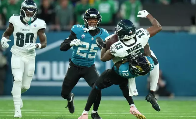 Jacksonville Jaguars wide receiver Travis Hunter (12) tackles Philadelphia Eagles wide receiver Dontayvion Wicks (13) during an NFL football game in London, Sunday, Oct. 11, 2026. (AP Photo/Alastair Grant)