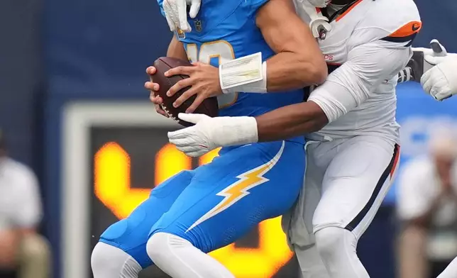 Los Angeles Chargers quarterback Justin Herbert, left, is sacked by Denver Broncos linebacker Nik Bonitto during the first half of an NFL football game, Sunday, Oct. 11, 2026, in Inglewood, Calif. (AP Photo/Scott Strazzante)