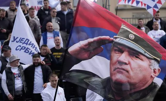 Supporters of Serbia's populist leader Aleksandar Vucic wave a flag shows a former Bosnian Serb wartime general Ratko Mladic during a pre-election rally of the ruling Serbian Progressive Party (SNS) ahead of early parliamentary elections in Novi Sad, Serbia, Friday, Oct. 16, 2026. (AP Photo/Darko Vojinovic)