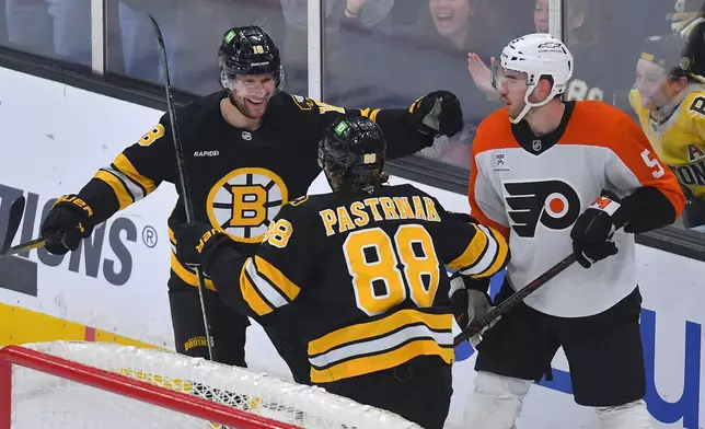Boston Bruins center Pavel Zacha (18) celebrates his goal with right wing David Pastrnak (88) as Philadelphia Flyers defenseman David Jiricek (5) looks on during the first period of an NHL hockey game Saturday, Oct. 10, 2026, in Boston. (AP Photo/Steven Senne)
