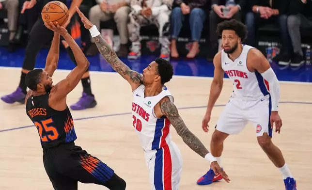 New York Knicks' Mikal Bridges (25) shoots over Detroit Pistons' John Collins (20) as Cade Cunningham (2) watches during the first half of an NBA basketball game Tuesday, Oct. 27, 2026, in New York. (AP Photo/Frank Franklin II)