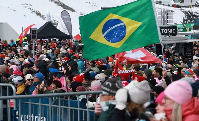 Supporters of Brazil's Lucas Pinheiro Braathen wave a Brazilian flag during an alpine ski, men's World Cup giant slalom, in Soelden, Austria, Sunday, Oct. 25, 2026. (AP Photo/Alessandro Trovati)