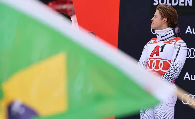 Brazil's Lucas Pinheiro Braathen listens to the national anthem on the podium after winning an alpine ski, men's World Cup giant slalom, in Soelden, Austria, Sunday, Oct. 25, 2026. (AP Photo/Marco Trovati)