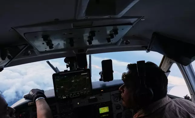Pilots Victor Torres from Mexico, right, and Jose Torres from Honduras fly an aircraft during a cloud seeding mission aimed at inducing rain as part of the Honduran government's efforts to address a prolonged drought at the Aguan river, in northern Honduras, Wednesday, Oct. 14, 2026. (AP Photo/Moises Castillo)