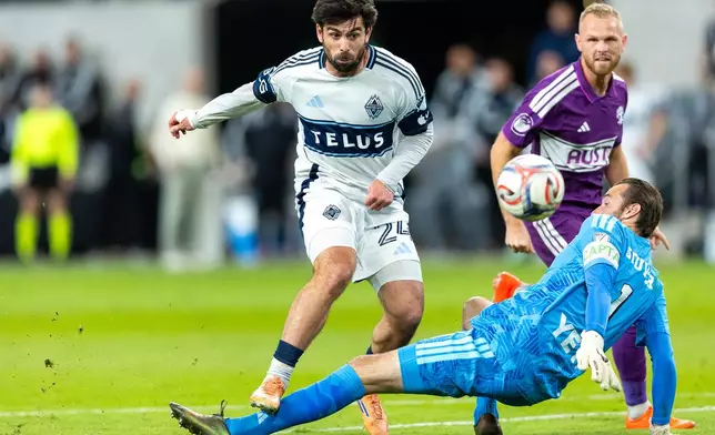 Austin FC goalkeeper Brad Stuver (1) makes a stop against Vancouver Whitecaps forward Brian White (24) with Austin FC defender Mikkel Desler (3) watching during the second half of an MLS soccer match in Austin, Texas, Saturday, Oct. 17, 2026. (AP Photo/Stephen Spillman)