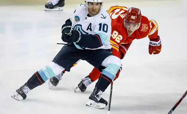 Seattle Kraken's Matty Beniers, left, checks Calgary Flames' Matvei Gridin, right, during the third period of an NHL hockey game in Calgary, Thursday, Oct. 1, 2026. (Jeff McIntosh/The Canadian Press via AP)