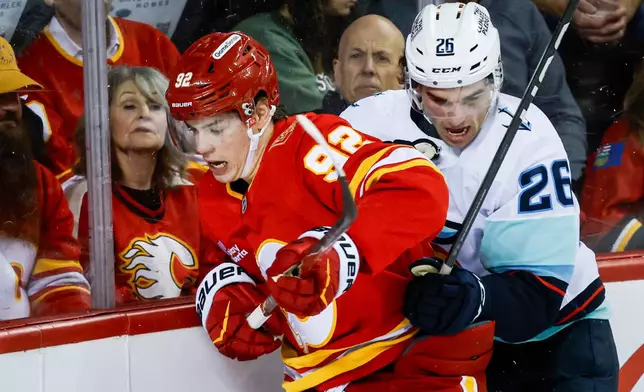Seattle Kraken's Ryan Winterton, right, checks Calgary Flames' Matvei Gridin (92) during the second period of an NHL hockey game in Calgary, Alberta, Thursday, Oct. 1, 2026.(Jeff McIntosh/The Canadian Press via AP)