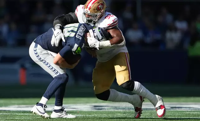 San Francisco 49ers defensive tackle Osa Odighizuwa (92) stops Seattle Seahawks quarterback Sam Darnold (14) during the first half of an NFL football game Sunday, Oct. 11, 2026, in Seattle. (AP Photo/Lindsey Wasson)