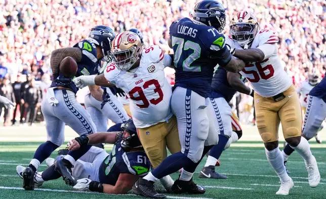 San Francisco 49ers defensive tackle Gracen Halton (93) strips the ball from Seattle Seahawks running back George Holani (36) during the first half of an NFL football game Sunday, Oct. 11, 2026, in Seattle. (AP Photo/Stephen Brashear)