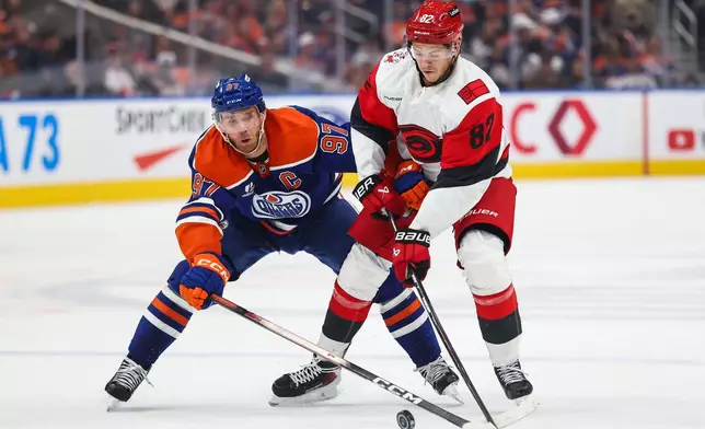 Edmonton Oilers' Connor McDavid (97) battles against Carolina Hurricanes' Jesperi Kotkaniemi (82) during the first period of an NHL hockey game in Edmonton, Alberta, Thursday, Oct. 22, 2026. (Codie McLachlan/The Canadian Press via AP)