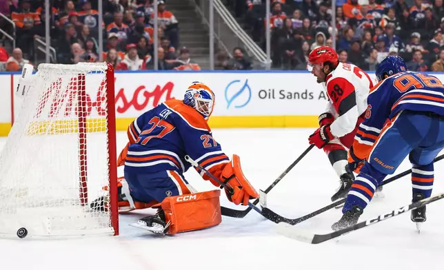 Edmonton Oilers goaltender Devon Levi (27) defends the net against Carolina Hurricanes' William Carrier (28) during the first period of an NHL hockey game in Edmonton, Alberta, Thursday, Oct. 22, 2026. (Codie McLachlan/The Canadian Press via AP)