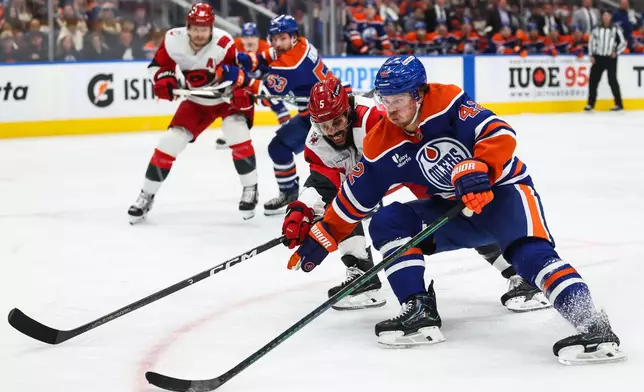 Edmonton Oilers' Kasperi Kapanen (42) protects the puck from Carolina Hurricanes' Jalen Chatfield (5) during the second period of an NHL hockey game in Edmonton, Alberta, Thursday, Oct. 22, 2026. (Codie McLachlan/The Canadian Press via AP)