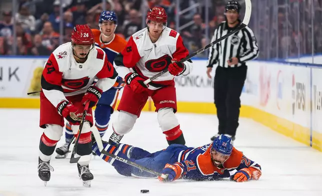 Edmonton Oilers' Mathieu Joseph (21) battles against Carolina Hurricanes' Seth Jarvis (24) and Juuso Valimaki (8) during the second period of an NHL hockey game in Edmonton, Alberta, Thursday, Oct. 22, 2026. (Codie McLachlan/The Canadian Press via AP)