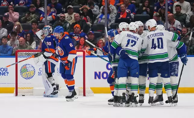 The Vancouver Canucks celebrate a goal by Brock Boeser as New York Islanders goaltender Ilya Sorokin (30) and Ryan Pulock (6) look away during the second period of an NHL hockey game Tuesday, Oct. 13, 2026, in Elmont, N.Y. (AP Photo/Frank Franklin II)