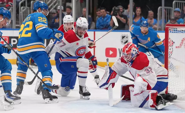 St. Louis Blues' Pius Suter (22) skates near a loose puck as Montreal Canadiens goaltender Jacob Fowler (32) and Kirby Dach (77) defend during the second period of an NHL hockey game Tuesday, Oct. 27, 2026, in St. Louis. (AP Photo/Jeff Roberson)