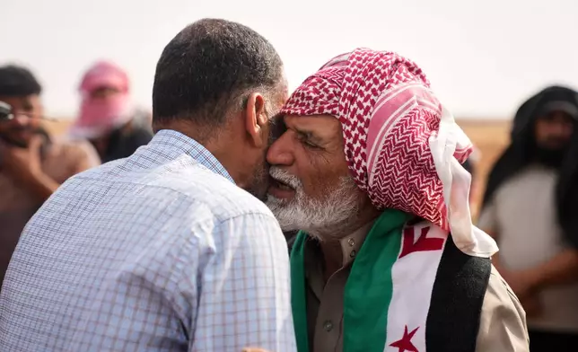 Masoud al-Salim, right, is comforted by a mourner during the funeral of his wife, son and three grandchildren, killed in a Jordanian airstrike, in Al-Tuff in southern Syria's Daraa province, Tuesday, Oct. 27, 2026, as Jordan acknowledged civilian deaths in strikes it said killed about 20 Islamic State militants. (AP Photo/Ghaith Alsayed)