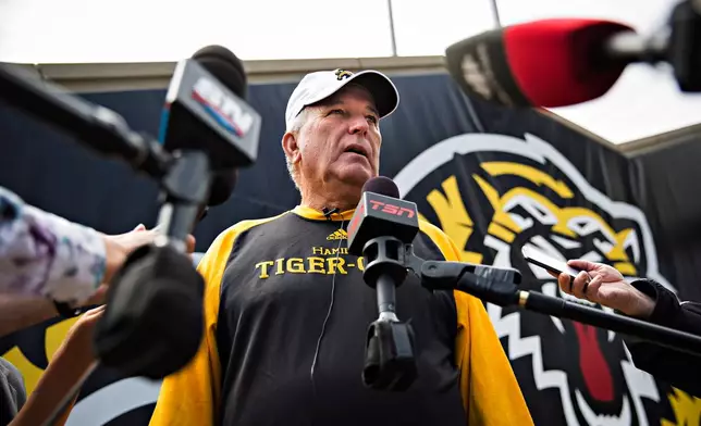 FILE - Hamilton Tiger-Cats head coach June Jones speaks to the media about the joint team and CFL decision to backtrack on the hiring of Art Briles as assistant coach following a practice in Hamilton, Ontario, Aug. 29, 2017. (Aaron Lynett/The Canadian Press via AP, File)