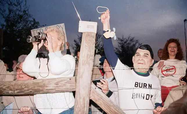 FILE - A toy bunny is hung in effigy by Jerry Jackson, of Atlanta Ga., wearing a Ronald Reagan mask, as the pro-death penalty crowd rejoices after the Theodore Bundy execution, Jan. 25, 1989, at sunrise in Starke, Fla. (AP Photo/Mark Foley, File)