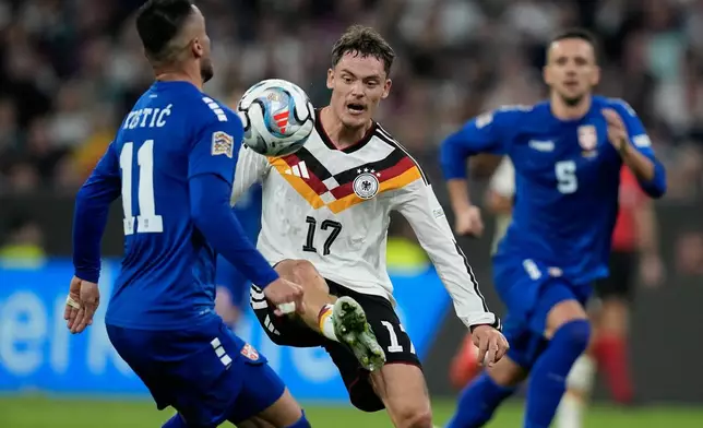 Germany's Florian Wirtz, center, and Serbia's Filip Kostic, left, challenge for the ball during the UEFA Nations League soccer match between Germany and Serbia in Munich, Germany, Thursday, Oct. 1, 2026. (AP Photo/Matthias Schrader)