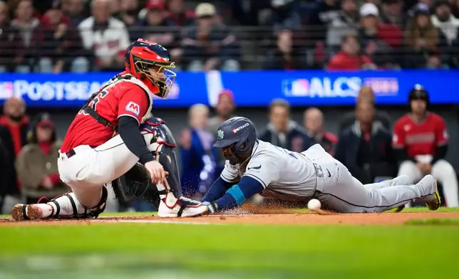 Tampa Bay Rays' Yandy Díaz scores past Cleveland Guardians catcher Patrick Bailey during the third inning in Game 4 of an American League Championship Series baseball game in Cleveland, Saturday, Oct. 17, 2026. (AP Photo/David J. Phillip)