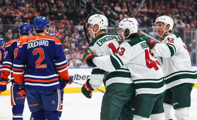 Minnesota Wild's Joel Eriksson Ek (14), third form right, Quinn Hughes (43) and Matt Boldy (12) celebrate a goal against the Edmonton Oilers during the first period of an NHL hockey game in Edmonton, Alberta, Tuesday, Oct. 20, 2026. (Codie McLachlan/The Canadian Press via AP)