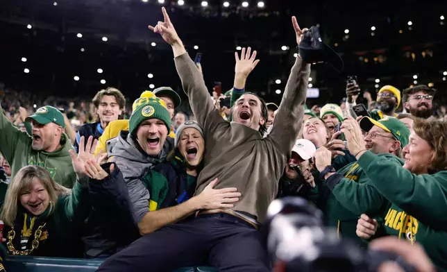 World Series Champions Milwaukee Brewers right fielder Sal Frelick, center, leaps into the stands as arrives with his baseball team during the first half of an NFL football game between the Green Bay Packers and the Carolina Panthers in Green Bay, Wis., Thursday, Oct. 29, 2026. (AP Photo/Matt Ludtke)