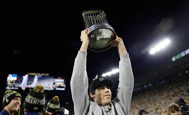 Milwaukee Brewers' Christian Yelich holds up the Commissioner's Trophy during the first half of an NFL football game between the Green Bay Packers and the Carolina Panthers in Green Bay, Wis., Thursday, Oct. 29, 2026. (AP Photo/Matt Ludtke)