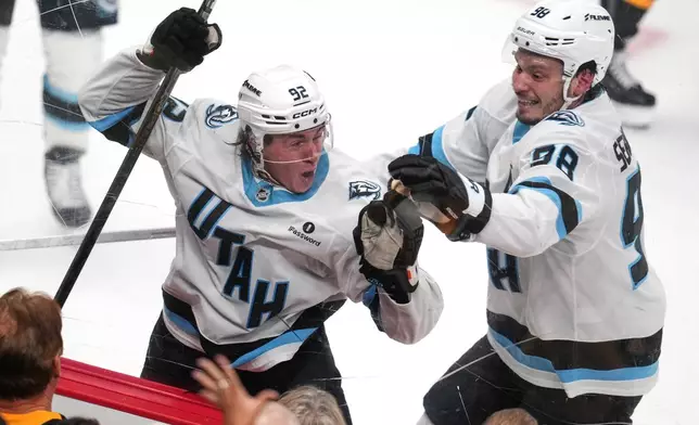 Utah Mammoth's Logan Cooley (92) celebrates after his goal with Mikhail Sergachev (98) during the third period of an NHL hockey game against the Pittsburgh Penguins in Pittsburgh, Thursday, Oct. 29, 2026. (AP Photo/Gene J. Puskar)