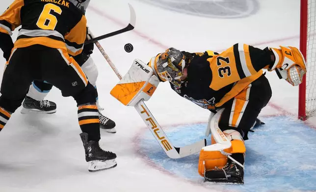 Pittsburgh Penguins goaltender Arturs Silovs (37) blocks a shot by Utah Mammoth's Logan Cooley with Penguins' Kaedan Korczak (6) defending during the first period of an NHL hockey game in Pittsburgh, Thursday, Oct. 29, 2026. (AP Photo/Gene J. Puskar)