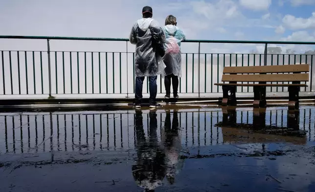 Tourists stand on a walkway overlooking Iguazu Falls in Foz do Iguacu, Brazil, Friday, Oct. 16, 2026. (AP Photo/Jorge Saenz)