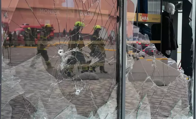 Firefighters are reflected in the broken glass after a Russian missile attack in central Kyiv, Ukraine, Thursday, Oct. 22, 2026. (AP Photo/Efrem Lukatsky)