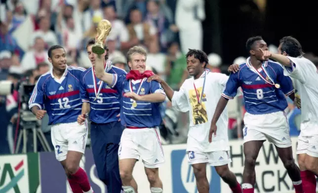FILE - Members of the French team celebrate their win against Brazil after the World Cup final on July 12, 1998, at the Stade the France in Saint-Denis, north of Paris, France. Walking the pitch, from left, are Thierry Henry, Laurent Blanc, captain Didier Deschamps, holding the trophy, Bernard Diomede, Marcel Desailly and Alain Boghossian. (AP Photo/Michel Lipchitz, File)