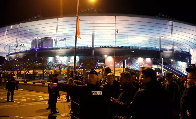 FILE - A police officer directs people outside the Stade de France stadium during the international friendly soccer France against Germany, in Saint Denis, outside of Paris, France, Nov. 13, 2015. (AP Photo/Michel Euler, File)