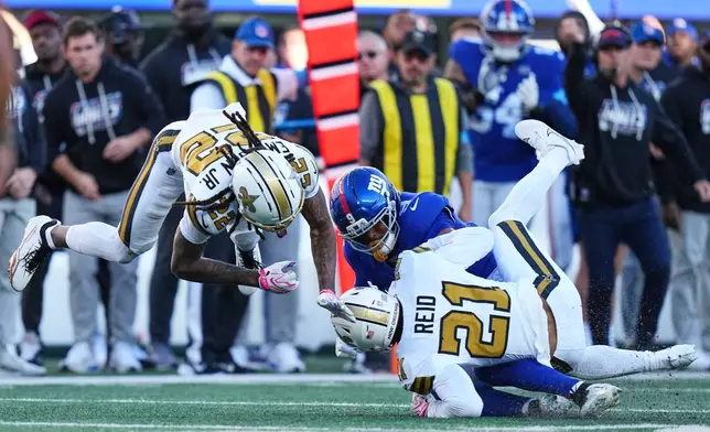 New Orleans Saints cornerback Martin Emerson Jr. (22) and Saints safety Justin Reid (21) tackle New York Giants tight end Isaiah Likely (9) during the second half of an NFL football game in East Rutherford, N.J., Sunday, Oct. 18, 2026. (AP Photo/Frank Franklin II)