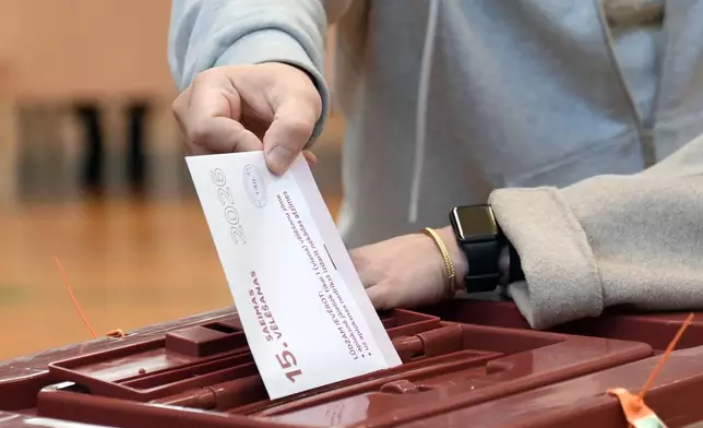 A voter casts his ballot at the parliamentary election at a polling station in Riga, Latvia, Saturday, Oct. 3, 2026. (AP Photo/Roman Koksarov)