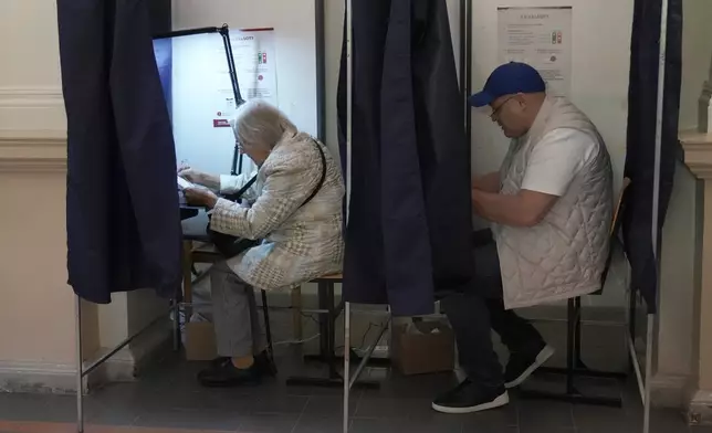 Voters fill in ballot papers at the parliamentary election at a polling station in Riga, Latvia, Saturday, Oct. 3, 2026. (AP Photo/Roman Koksarov)