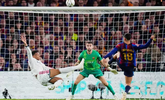 Real Madrid's Kylian Mbappe, left, attempts a shot at goal and misses in front of Barcelona's Gerard Martin, right, and Barcelona's goalkeeper Joan Garcia during a Spanish La Liga soccer match between FC Barcelona and Real Madrid in Barcelona, Spain, Sunday, Oct. 25, 2026. (AP Photo/Jose Breton)