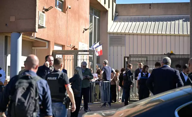 Police officers stand in front the Joseph Lakanal middle school after police have detained a 14-year-old pupil suspected in a rare school shooting, in Aubagne, France, Monday Oct. 12, 2026. (AP Photo/Philippe Magoni)