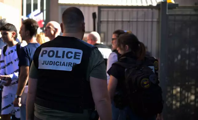 A police officer stands in front the Joseph Lakanal middle school after police have detained a 14-year-old pupil suspected in a rare school shooting, in Aubagne, France, Monday Oct. 12, 2026. (AP Photo/Philippe Magoni)