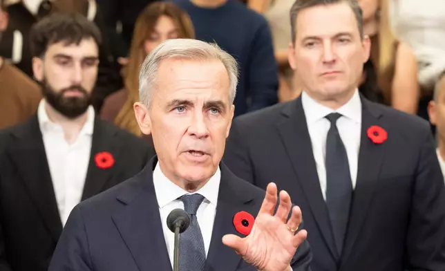 Prime Minister Mark Carney, centre, flanked by Aiden Gomez, left, co-founder and CEO of Cohere and Minister of Artificial Intelligence and Digital Innovation Evan Solomon, right, announces an investment of up to $1.6 billion in Canadian AI company Cohere, in Montreal on Thursday, Oct. 29, 2026. (Christinne Muschi /The Canadian Press via AP)