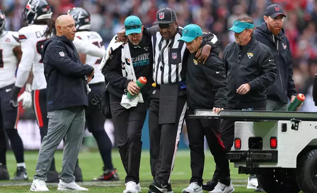 Umpire Larry Smith is assisted from the field after getting injured during an NFL football game between Houston Texans and Jacksonville Jaguars in London, Sunday, Oct. 18, 2026. (AP Photo/Ian Walton)