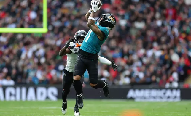 Jacksonville Jaguars wide receiver Parker Washington (11) makes a catch as Houston Texans cornerback Kamari Lassiter (3) closes in during an NFL football game in London, Sunday, Oct. 18, 2026. (AP Photo/Ian Walton)