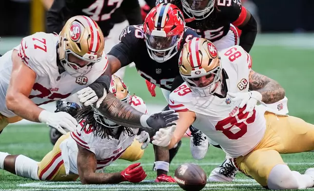 San Francisco 49ers' Dominick Puni (77), Luke Farrell (89) and Atlanta Falcons' Gervon Dexter Sr., center, scramble to recover a Jordan James fumble during the first half of an NFL football game in Atlanta, Sunday, Oct. 25, 2026. (AP Photo/Brynn Anderson)