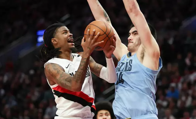Portland Trail Blazers guard Ja Morant (1) drives to the basket as Memphis Grizzlies center Zach Edey (14) defends during the second half of an NBA basketball game Thursday, Oct. 29, 2026, in Portland, Ore. (AP Photo/Amanda Loman)