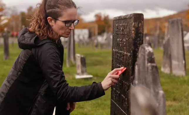 Caitlin Abrams, who became popular on TikTok for her grave cleaning videos, scrapes away moss and lichen from a gravestone at a cemetery in Rupert, Vt., Wednesday, Oct. 14, 2026. (AP Photo/Amanda Swinhart)