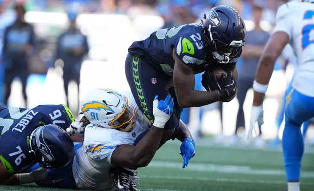 Seattle Seahawks running back Emanuel Wilson (23) is tackled by Los Angeles Chargers defensive tackle Nick Barrett (91) during the second half of an NFL football game, Sunday, Oct. 4, 2026, in Seattle. (AP Photo/Lindsey Wasson)