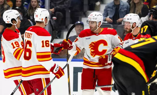Calgary Flames' Matthew Coronato (27) celebrates after his goal against the Vancouver Canucks with teammates during the first period of an NHL hockey game in Vancouver, British Columbia, Saturday, Oct. 3, 2026. (Jacob Mallari/The Canadian Press via AP)